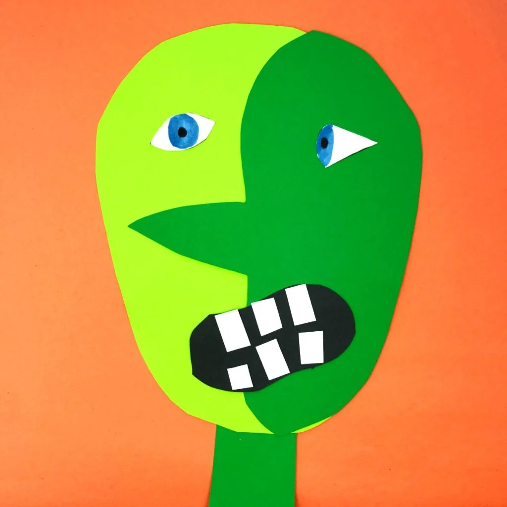 Frankenstein face taking shape with colored in eyes, a black mouth glued on, and white teeth from construction paper