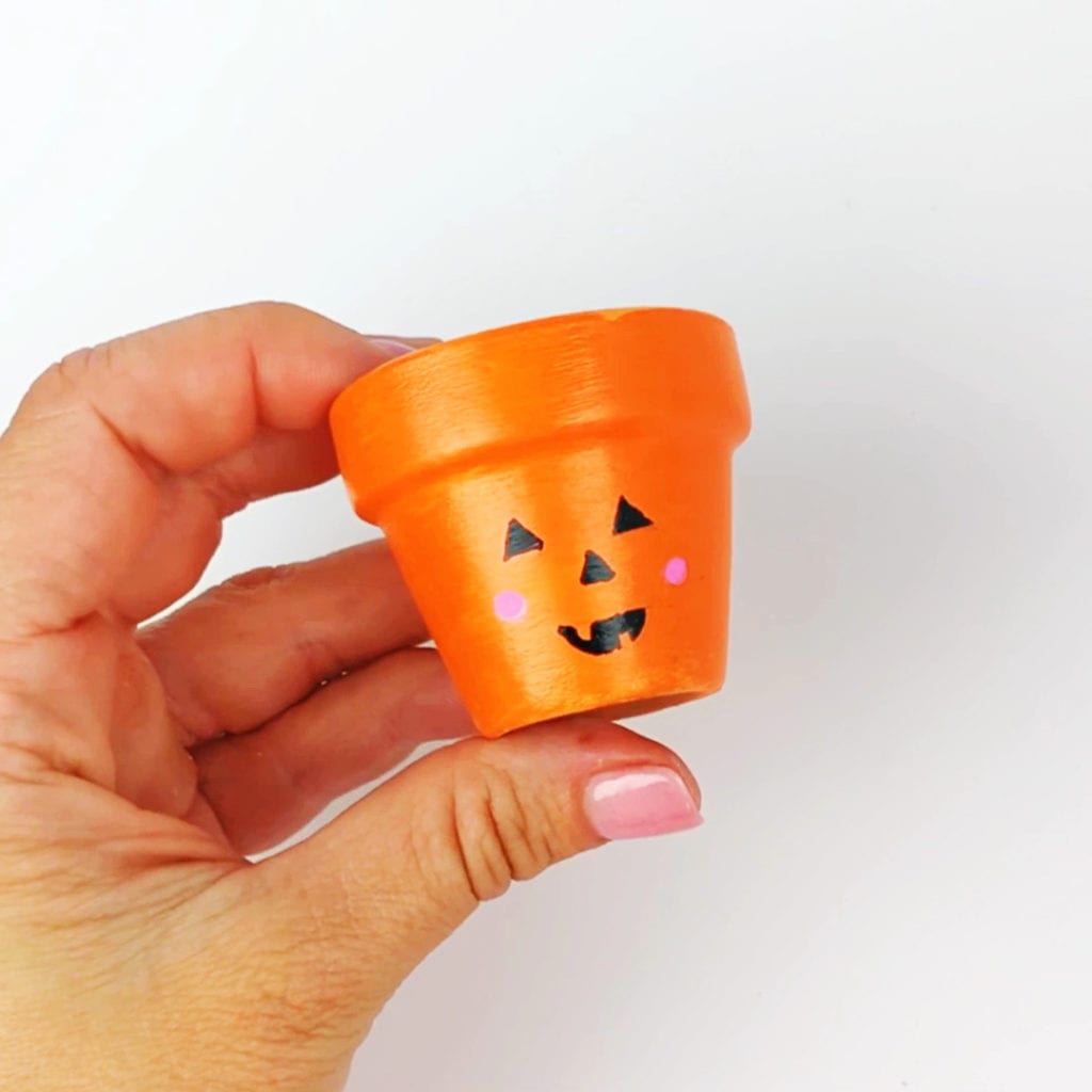 Pumpkin painted on a mini flower pot as an example candy holder craft for Halloween