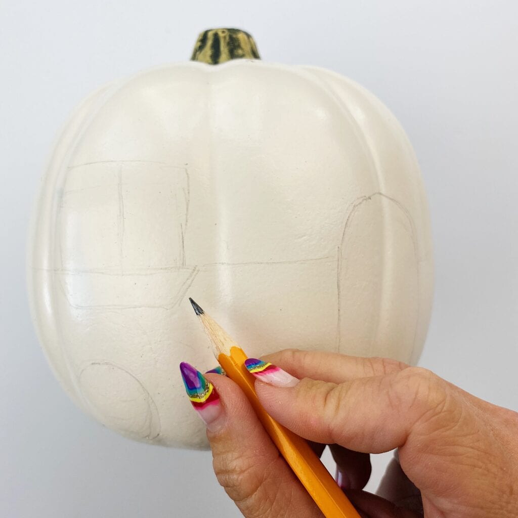 Sketching the design on a white pumpkin