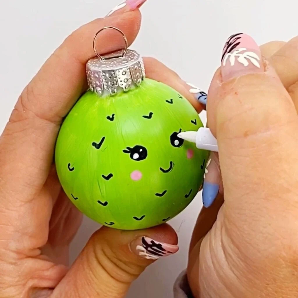 Painting kawaii eyes on a cactus Christmas tree ornament face