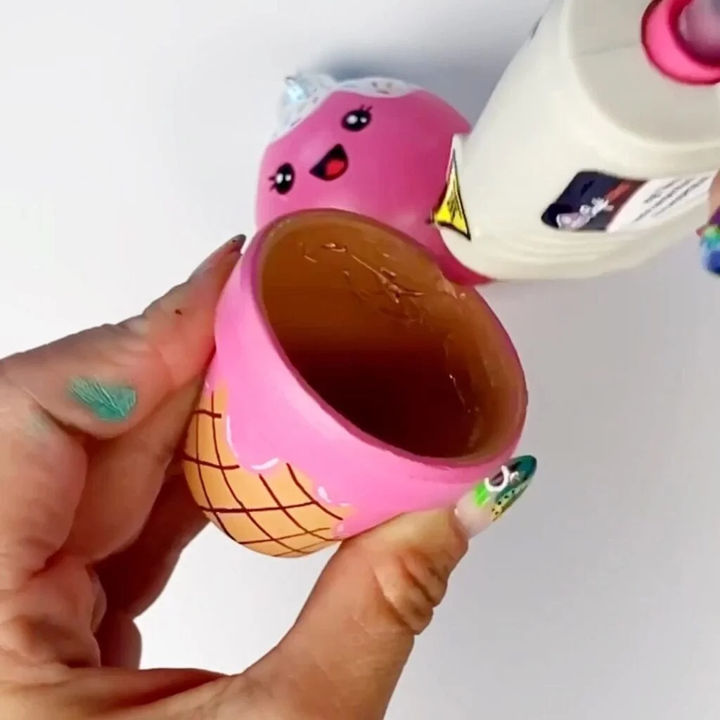 Applying hot glue to the flower pot so we can glue the Christmas bauble inside of it