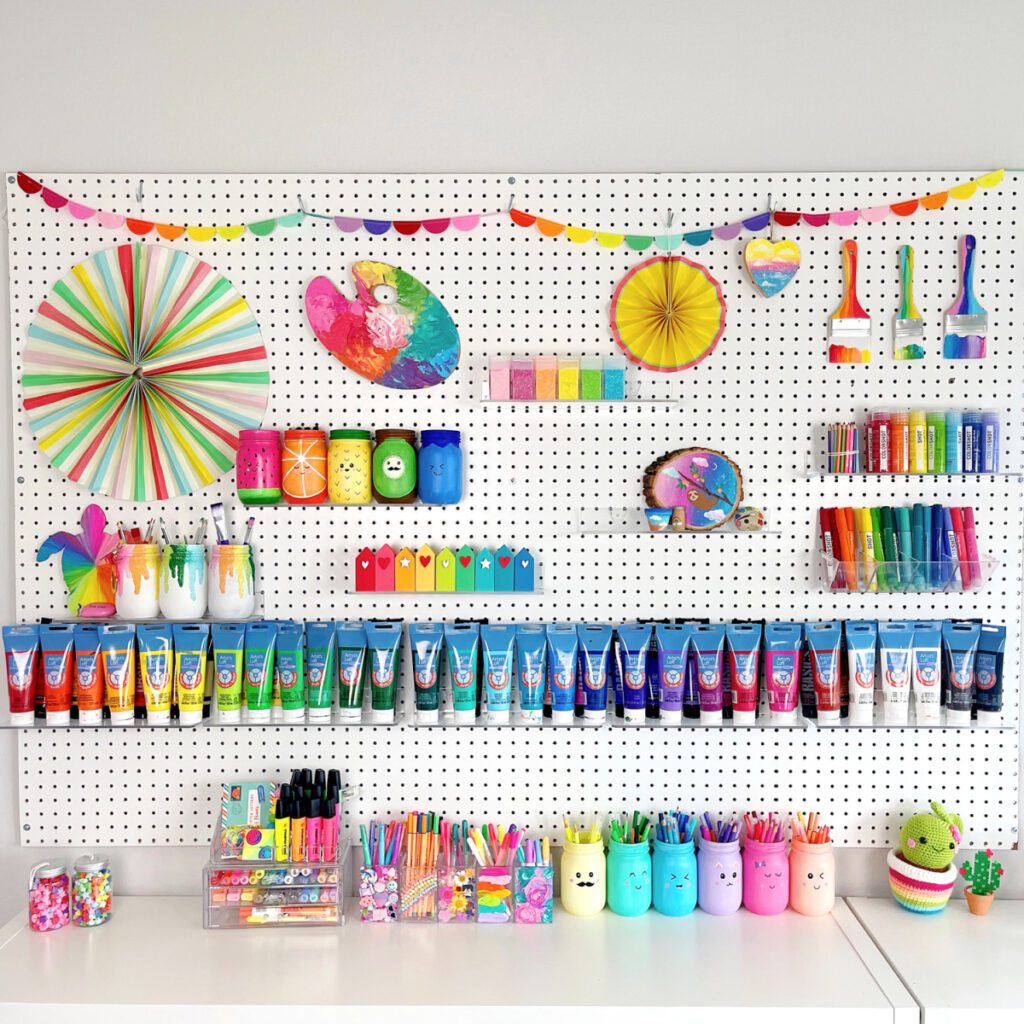 Pegboard filled with organized colorful craft supplies including paints