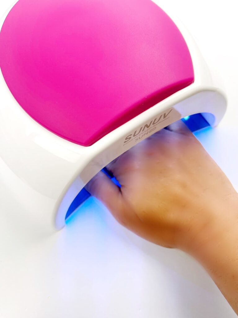 Hand inside a uv lamp for gel nails to set them